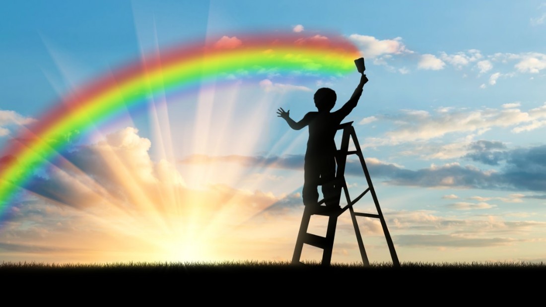 Boy painting a rainbow across the sky